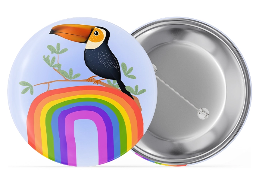 spilla rotonda con spillo con il disegno infantile di un tucano su un arcobaleno con sfondo blu