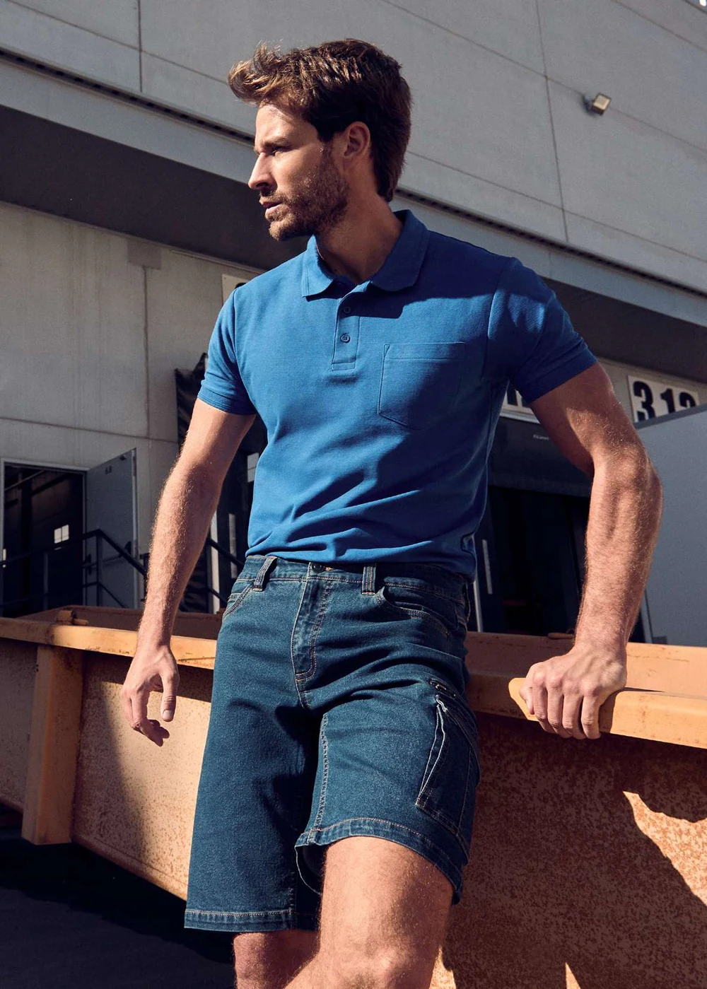 Modelo com polo azul e bermudas de trabalho Roly WRK